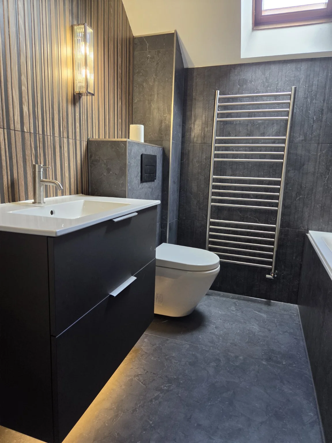 Dark charcoal bathroom with wood-effect feature wall and illuminated vanity