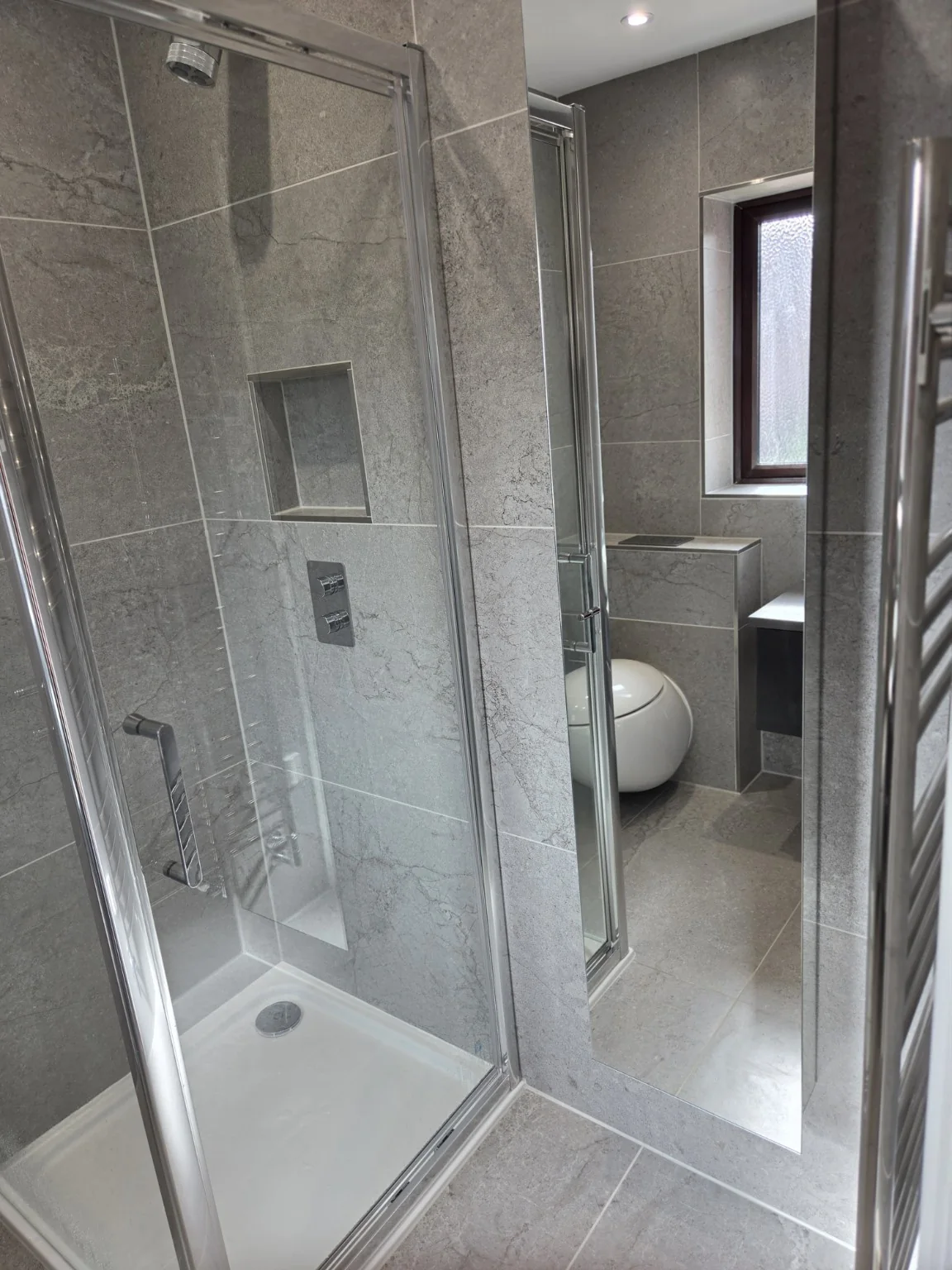 Grey tiled shower room with full-height mirror