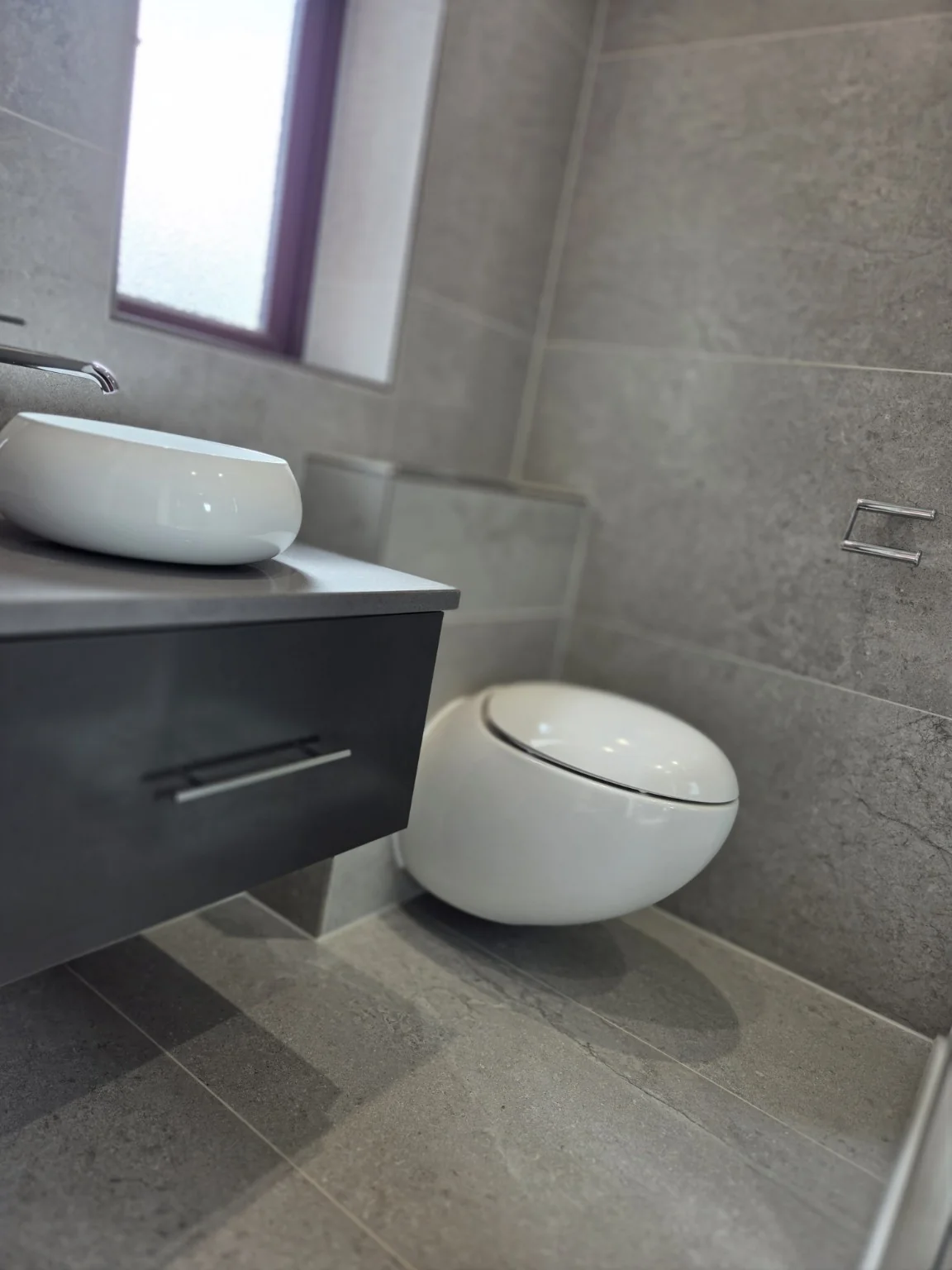 Grey stone shower room close-up with basin, toilet and shower screen