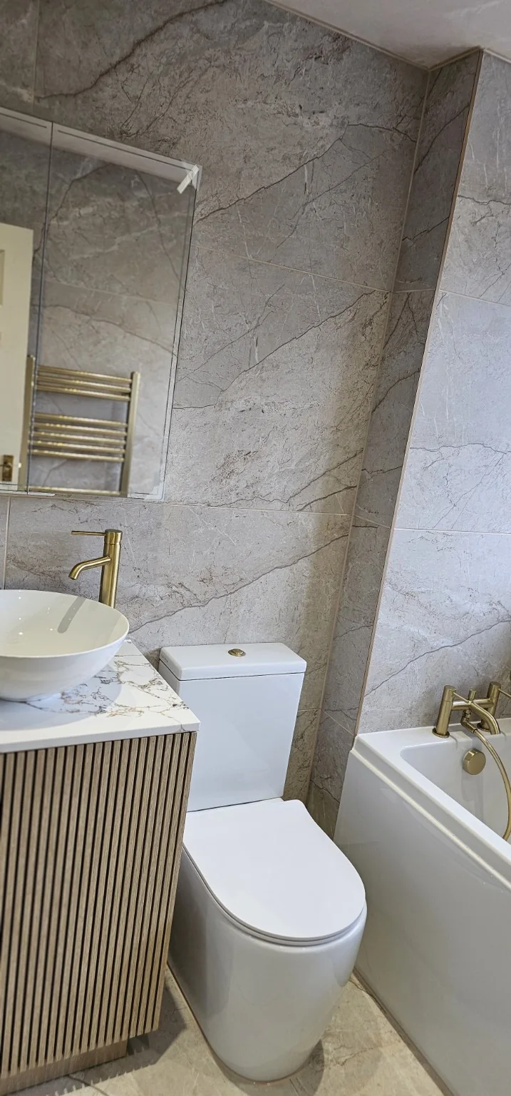 Stone and gold bathroom showing vanity, toilet and bath